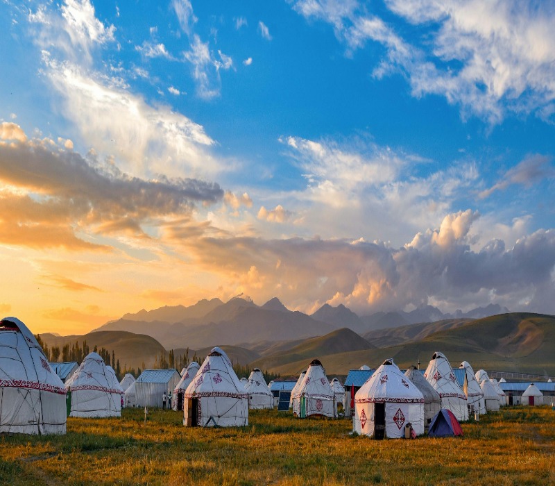 White yurts scattered across a mountain valley in Xinjiang.