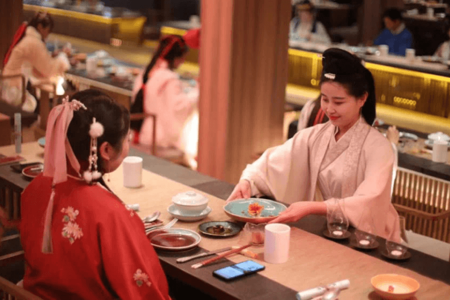 Two females in traditional Chinese clothing enjoying a cultural banquet, symbolizing family memories and experiences in China
