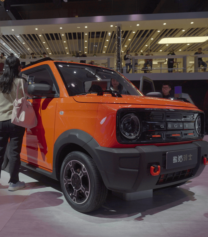 Geely Geometry EV in bright orange displayed at a China automobile exhibition