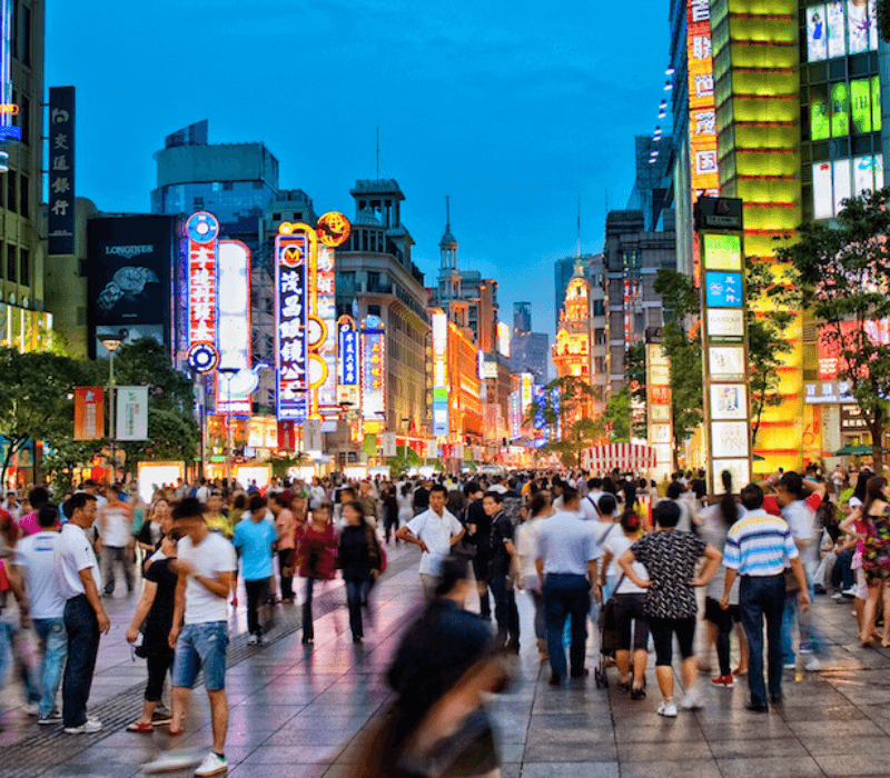 Crowded Nanjing Road in Shanghai at night with lights and active shoppers